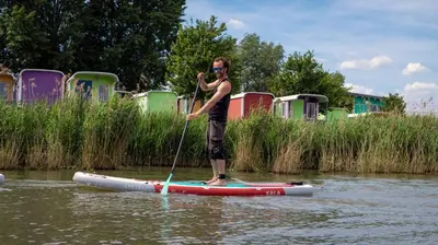a man standing on a paddle board in the water at Camping Zeeburg Amsterdam in Amsterdam