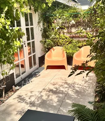 a patio with two orange chairs and plants at The Forester Schoorl in Schoorl