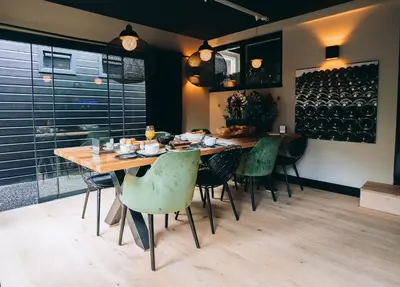 a dining room with a wooden table and green chairs at B&B Bardot in Purmerend