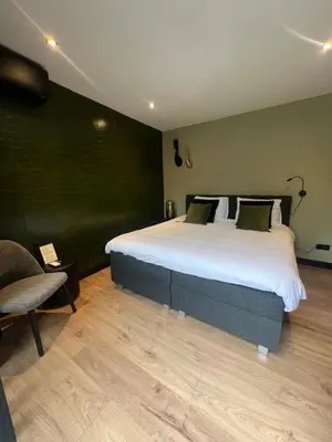 a bedroom with a large bed and a chair at B&B Bardot in Purmerend