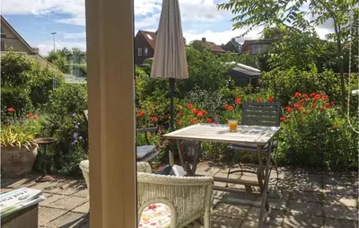 a patio with a table and chairs and flowers at Zeemeermin in Egmond aan Zee