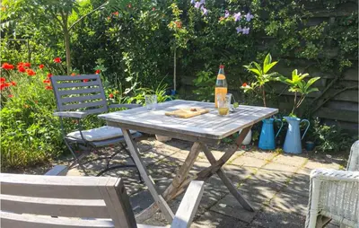 a picnic table with a bottle of beer and a chair at Zeemeermin in Egmond aan Zee