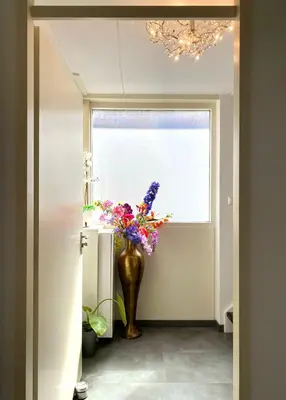 a vase with flowers in a hallway with a window at Home Inn Zandvoort the First Floor 4 Persons, 2 bedrooms, Free Parking! in Zandvoort