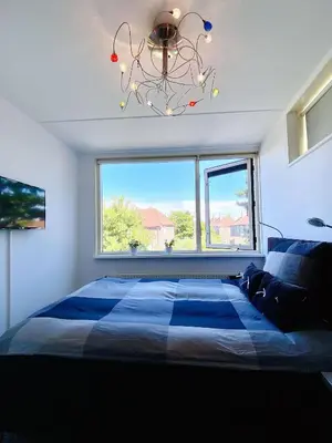 a bedroom with a large bed with a large window at Home Inn Zandvoort the First Floor 4 Persons, 2 bedrooms, Free Parking! in Zandvoort