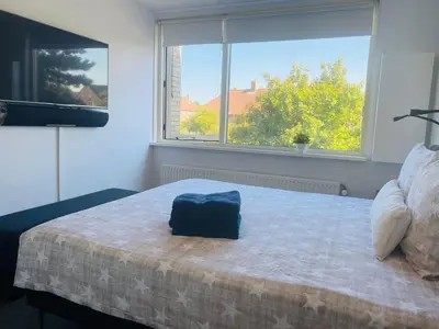 a bedroom with a bed and a large window at Home Inn Zandvoort the First Floor 4 Persons, 2 bedrooms, Free Parking! in Zandvoort