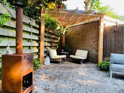 an outdoor patio with two chairs and a brick wall at Holiday home De Heer van Bergen in Bergen