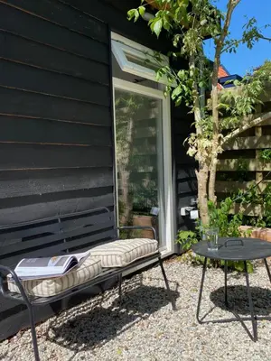 a chair and a table next to a house at Holiday home De Heer van Bergen in Bergen