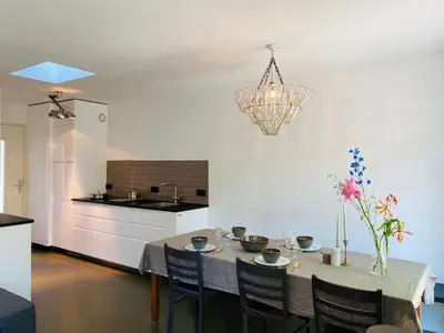 a kitchen with a table with chairs and a chandelier at Holiday home De Heer van Bergen in Bergen