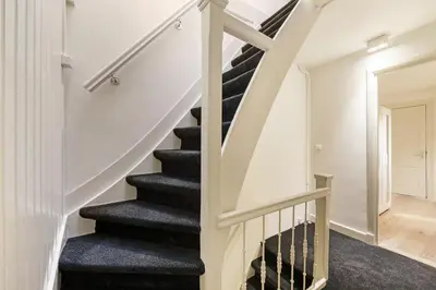 a staircase in a home with white walls and black carpet at Adam's Suite in Amsterdam