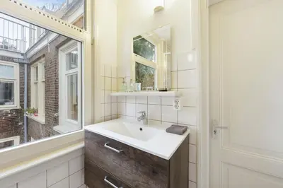 a bathroom with a sink and a mirror and a window at Adam's Suite in Amsterdam