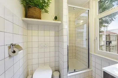 a bathroom with a shower and a toilet and a window at Adam's Suite in Amsterdam