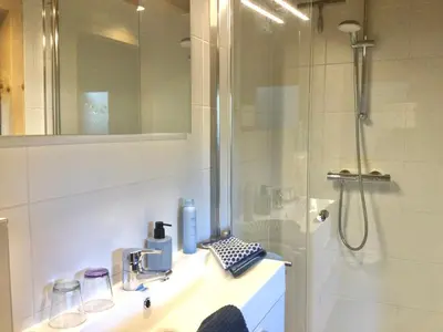 a bathroom with a shower and a sink and a mirror at Klein Langeveld in Noordwijkerhout