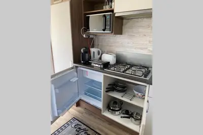 a small kitchen with a stove and a microwave at Cheerful and relaxing chalet Viena(Park deHorn824) in Dirkshorn