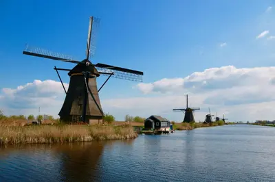 two windmills on a river with a house and a building at Eelhouse private studio in Amsterdam