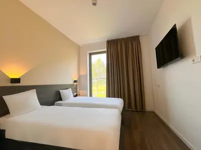 a hotel room with two beds and a window at HOTELUX Amsterdam Airport Hotel in Hoofddorp