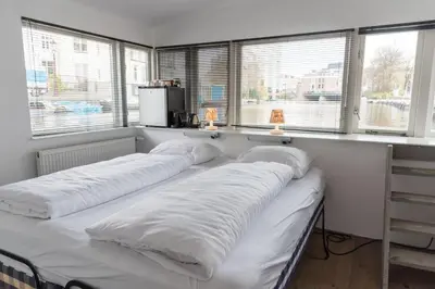 three beds in a room with large windows at HouseBoat next to AMSTEL in Amsterdam