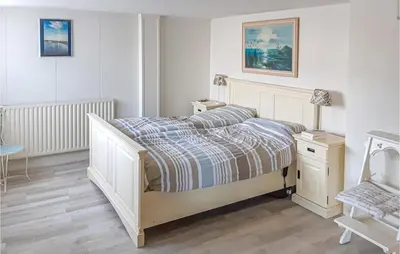 a white bedroom with a bed and a chair at Elfrank in Bergen aan Zee