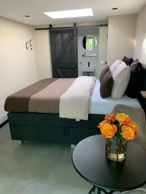 a bedroom with a bed and a table with flowers at Petite Maison Bennebroek in Bennebroek