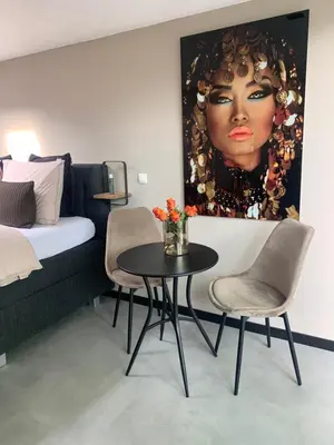 a room with a table and chairs and a picture of a woman at Petite Maison Bennebroek in Bennebroek