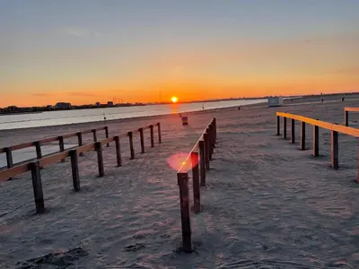 a sunset on the beach with a pier at Bed & Beach Amsterdam in Amsterdam