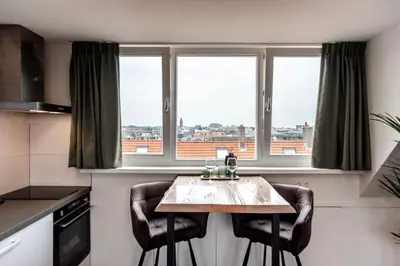 a kitchen with a table with chairs in front of windows at Seawave Studio in Zandvoort