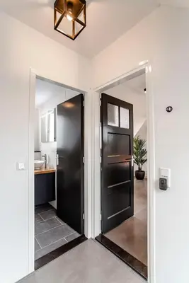 a hallway with a black door and a sink at Seawave Studio in Zandvoort