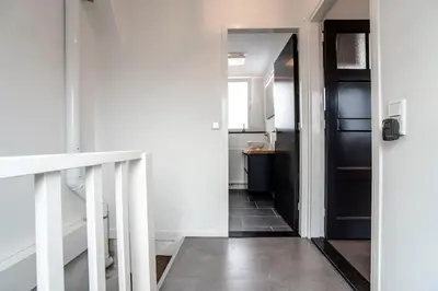 a hallway with a black door and white walls at Seawave Studio in Zandvoort