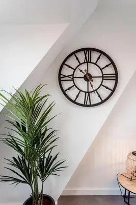 a clock on a wall with a plant in a room at Seawave Studio in Zandvoort