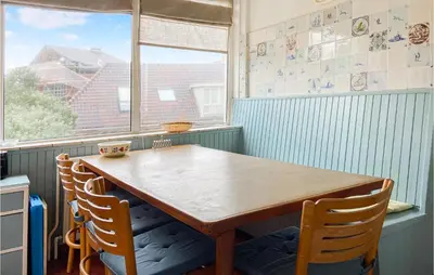 a wooden table and chairs in a room with a window at Blaauburgh in Bergen aan Zee