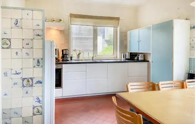 a kitchen with white cabinets and a table and a window at Blaauburgh in Bergen aan Zee