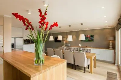 a vase of red flowers on a wooden table in a kitchen at Time Out Beach House in Zandvoort