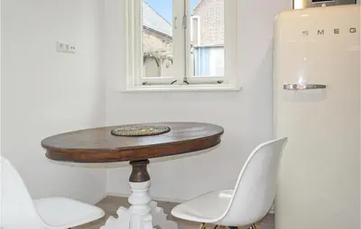 a table and two chairs and a refrigerator in a room at Duinviooltje 2 in Bergen aan Zee