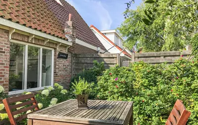 a garden with a wooden table and chairs in front of a house at Duinviooltje 2 in Bergen aan Zee