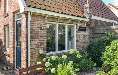 a brick house with a window and a bench at Duinviooltje 2 in Bergen aan Zee