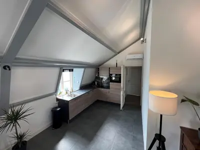 an attic kitchen with a sink and a table at Appartement Warmond in Warmond