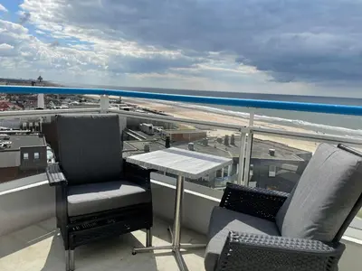a balcony with a table and chairs and the ocean at Droomvakanties Egmond Zeezicht in Egmond aan Zee