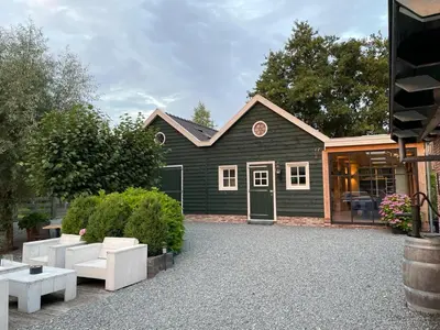 a black house with white furniture in front of it at Flora’s B&B in Landsmeer