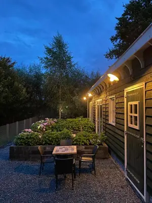 a patio with a table and chairs next to a building at Flora’s B&B in Landsmeer