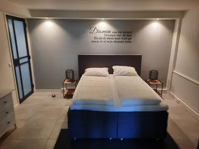 a large bed in a room with a sign on the wall at Have a nice stay! - Souterrain Edelweiss in Noordwijk