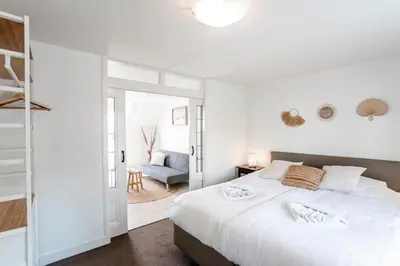 a bedroom with a large white bed and a chair at Sand & Dunes Apartment in Zandvoort