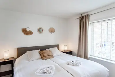 a bedroom with a large white bed with two night stands at Sand & Dunes Apartment in Zandvoort