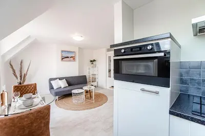 a kitchen with a stove and a living room at Sand & Dunes Apartment in Zandvoort