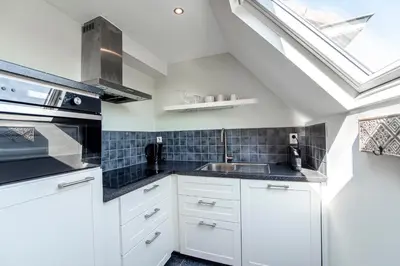 a kitchen with white cabinets and a skylight at Sand & Dunes Apartment in Zandvoort