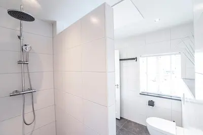 a white bathroom with a shower and a toilet at Sand & Dunes Apartment in Zandvoort