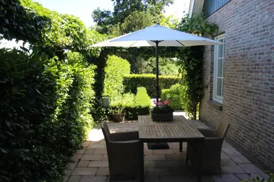 a table with an umbrella on a patio at Studio Bed and Breakfast Zaans Moment in Assendelft