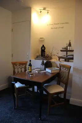 a dining room table with chairs and a writing on the wall at Studio Bed and Breakfast Zaans Moment in Assendelft