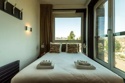 a bedroom with a large bed with a large window at Hotel Mosaic Apartments in Amsterdam