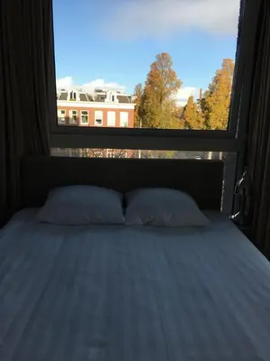 a bed in a room with a large window at Hotel Mosaic Apartments in Amsterdam