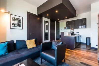 a living room with a couch and a chair and a kitchen at Hotel Mosaic Apartments in Amsterdam