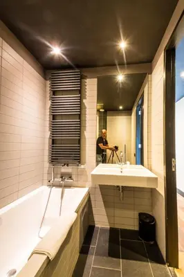 a man taking a picture of a bathroom with a tub and a sink at Hotel Mosaic Apartments in Amsterdam
